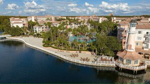 A resort with a pool, palm trees, and a water body. - Spacious 1-bedroom 1 bath villa with full kitchen beautiful Orlando with AC (Orlando)