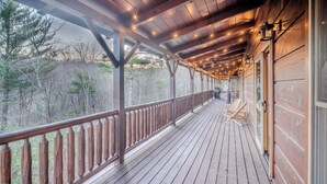 A wooden deck with string lights, a railing, and a view of trees. - Vibrant Spacious Mountain Estate with Heated Pool & Hot Tub in Suches (Suches)