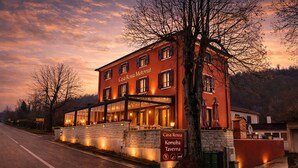 Un edificio rojo con los rótulos 'Casa Rossa Motovuon' y 'Komoba Tavern', que presenta una fachada de piedra y una entrada de vidrio.