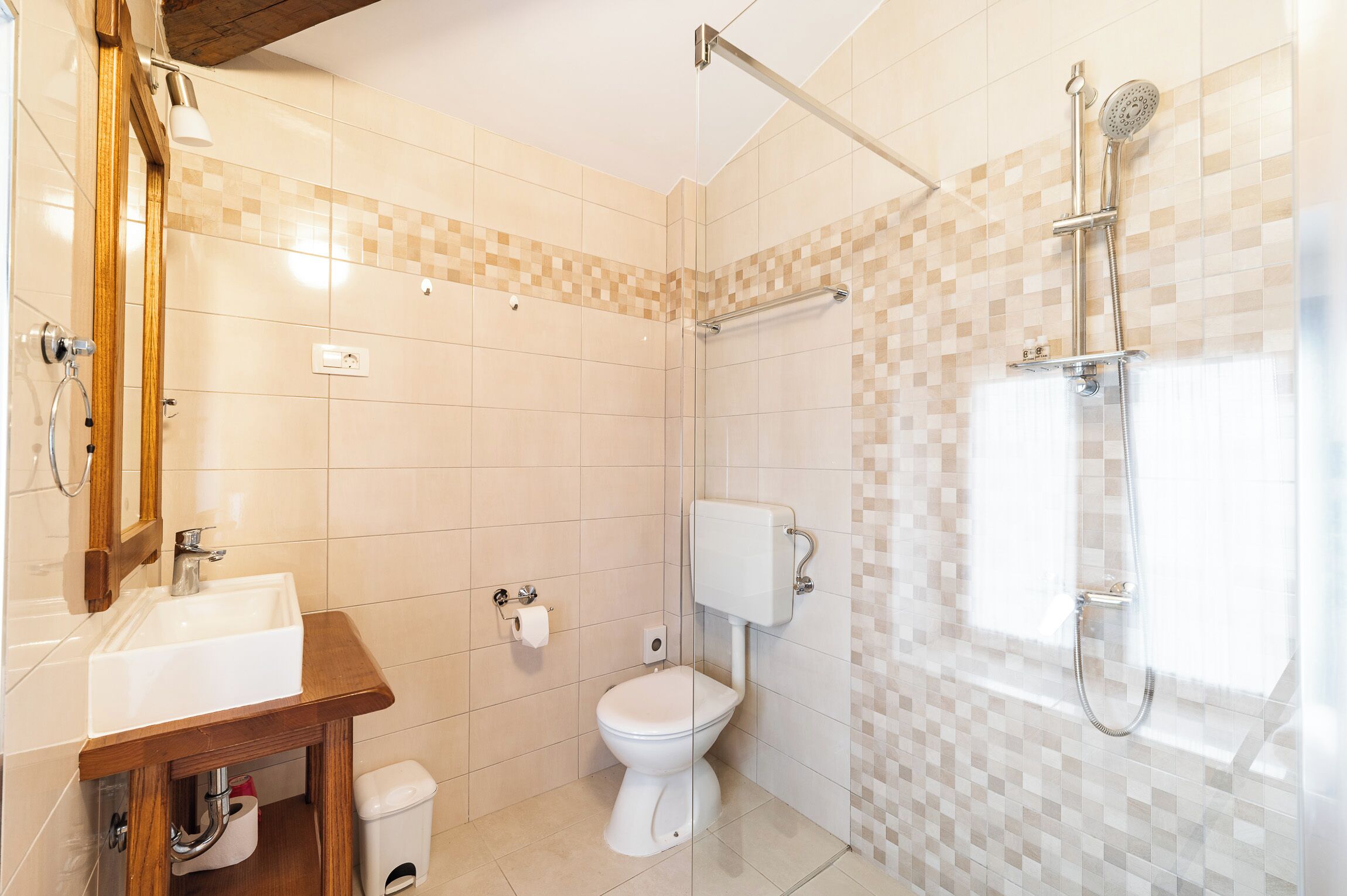 Un baño con ducha, inodoro, lavamanos y espejo.