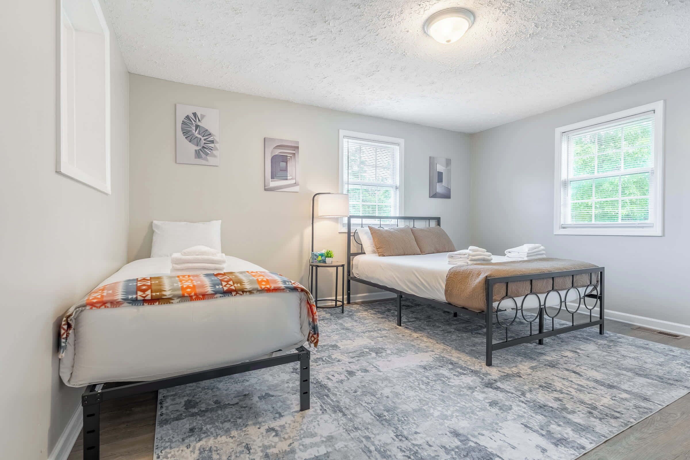 A bedroom with two beds, a small table, and a lamp.