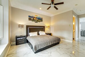 Une chambre avec un grand lit, deux tables de chevet, un ventilateur de plafond et des œuvres d’art accrochées au mur.