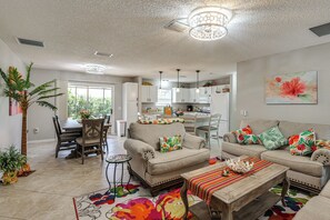 A living room with a sofa, coffee table, and a dining area with chairs and a table. - Golf, Dine & Relax Poolside! The Villages Retreat (The Villages)