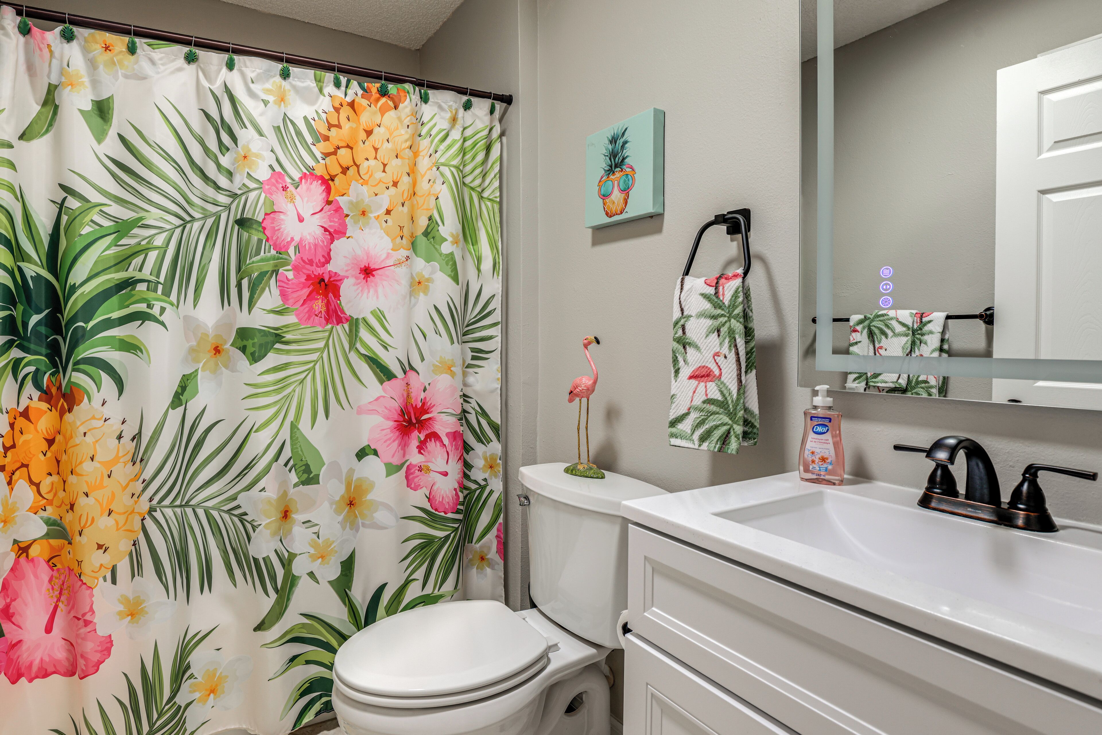 Baño con inodoro, lavabo y cortina de ducha estampada con motivos florales.