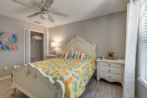 A bedroom with a bed, nightstands, a ceiling fan, a bedside lamp, and a window with blinds. - Golf, Dine & Relax Poolside! The Villages Retreat (The Villages)