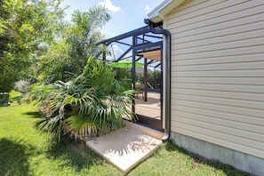 A house with a covered patio area, a concrete step leading to the entrance, and a variety of green plants. - Golf, Dine & Relax Poolside! The Villages Retreat (The Villages)