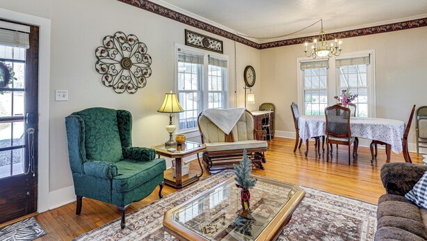 A living room with a green armchair, a coffee table, and a dining area with a table and chairs.