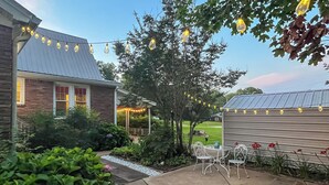 A patio with outdoor seating, string lights, and a garden area.