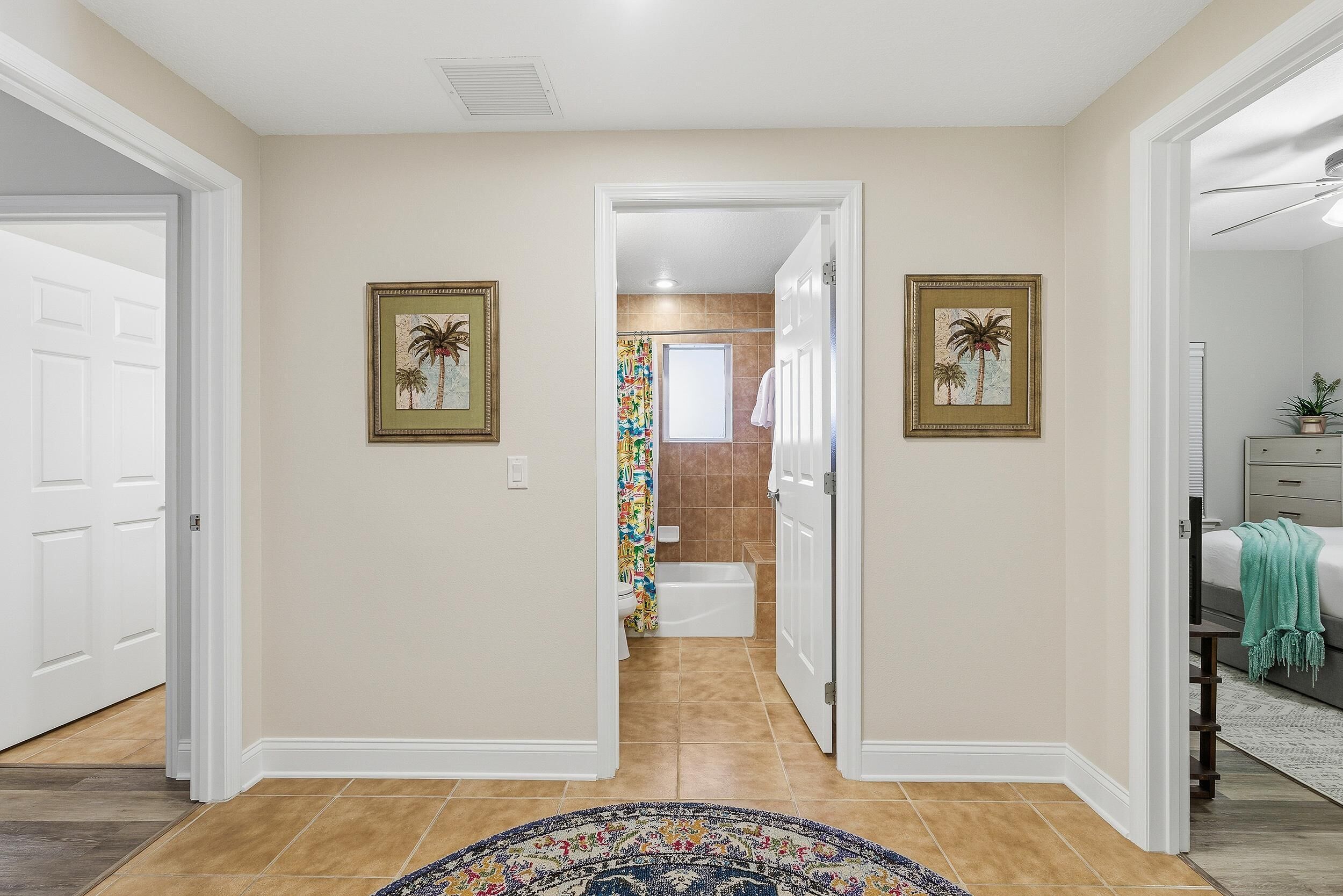 A hallway with beige walls, a patterned rug, and two framed pictures.