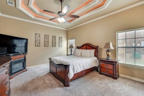 Ein Schlafzimmer mit Bett, Schminktisch, Fernseher und Deckenventilator.
