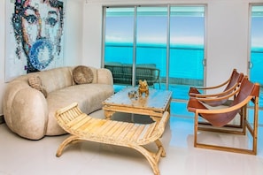 A living room with a sofa, a coffee table, a wicker chair, and a set of wooden chairs. - Super Luxury Beachfront 4BR w/ Ocean view Balcony (Cartagena)