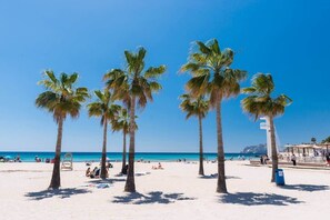 Ein Strand mit Palmen, blauem Himmel und entspannten Menschen.