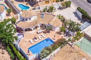 Eine Villa mit Swimmingpool, Gartenmöbeln und einem Garten.