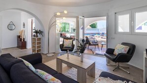 A modern living room with a sofa, chairs, a coffee table, and a view of an outdoor pool area. - Villa La Ola - 200m from the beach (Benissa)