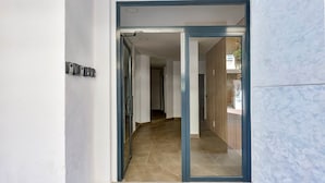 Un pasillo con una puerta de cristal que da a una habitación con piso de madera y vistas al exterior.