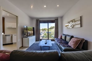 A modern living room with a sofa, a coffee table, and a TV. There is a balcony with a view of the outdoors. - Apartment 58 - Moraira city center (Moraira)