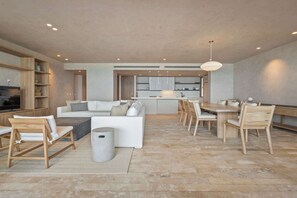 Ein modernes Wohnzimmer mit Sofa, Couchtisch und Essbereich mit Stühlen und Tisch.
