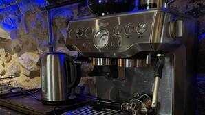 Una máquina de espresso de acero inoxidable con pantalla digital, espumador de leche y porta filtro sobre una encimera de madera.