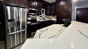 Una cocina moderna con armarios de madera oscura, electrodomésticos de acero inoxidable y encimera de mármol.