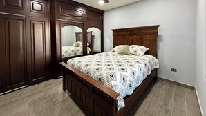 Un dormitorio con una cama de madera, un ventilador de techo y un espejo grande.