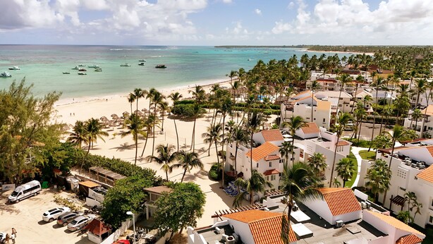Un resort costero con acceso a la playa, palmeras y vistas al océano.