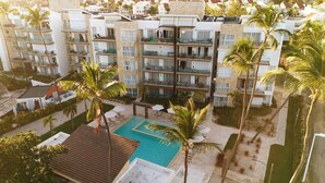 Un hotel de varios pisos con balcones, piscina y palmeras.
