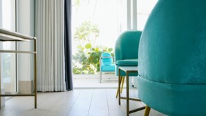 Una habitación luminosa con un sillón color turquesa, una mesita y vistas a zonas verdes.