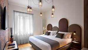 A modern bedroom with a large bed, bedside tables, a TV, and a window with curtains.