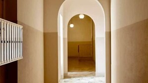 A hallway with a tiled floor, an arched doorway, and a light fixture on the ceiling.