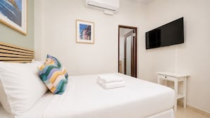 A hotel room with a bed, a TV, a small table, and a framed picture on the wall. - Room 5: Modern City Stay in Santurce (San Juan)
