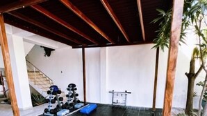 A covered outdoor area with a tiled floor, a blue mat, and a staircase leading to an upper level. - HOTEL Y PISCINA VILLA MARIA URIBIA (Uribia)