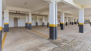 Un parking à étages, avec des planchers en béton et des piliers ornés de rayures jaunes et noires.