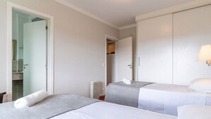 Une chambre d’hôtel avec deux lits, une salle de bain visible à travers une porte ouverte et un radiateur.