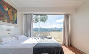 Une chambre à coucher avec un lit, un tableau, une vue sur l’extérieur et une fenêtre avec des rideaux.