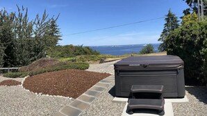 A hot tub in a landscaped garden with a view of the ocean. - Sweet Caroline Water View (Port Angeles)