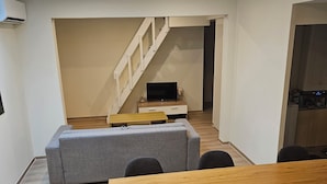 Un espace de vie moderne comprenant un coin repas, un canapé, un téléviseur et un escalier.