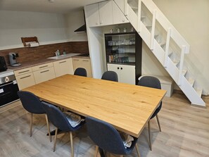 A modern kitchen with a wooden table, chairs, and a built-in cabinet with glass doors.