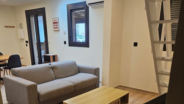 Un salon moderne avec un canapé, une table basse en bois et un téléviseur.