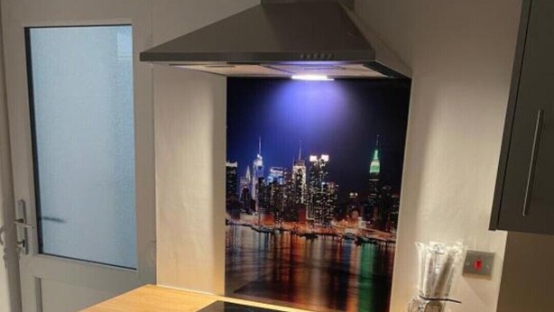 Una cucina compatta con piano cottura integrato, forno e un poster con vista sulla città.
