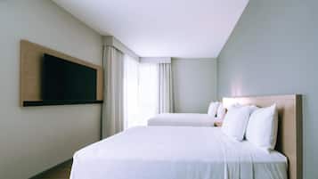 A hotel room with a large bed, a TV mounted on the wall, and a window with curtains.