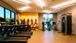 Un gimnasio con cintas de correr, bicicletas estáticas y máquinas de pesas.