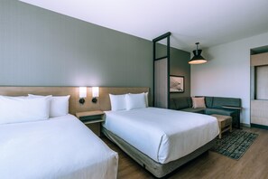 A hotel room with two beds, a nightstand, a seating area with a sofa, and a wall-mounted lamp. - Hyatt Place Ontario Airport (Ontario)