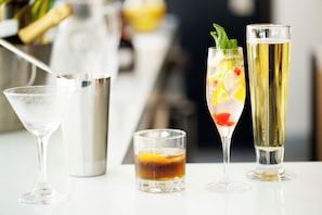 Tres tipos diferentes de vasos con bebidas, un shaker de cócteles y una botella de champán.