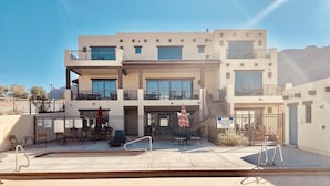 A multi-story building with balconies, outdoor seating, and a pool area.