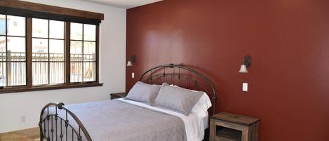 A bedroom with a bed, nightstands, a window, and a red wall.