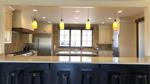 A modern kitchen with a large island, bar stools, and pendant lighting.