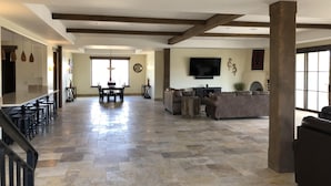 A spacious living area with a dining table, sofas, and a TV.