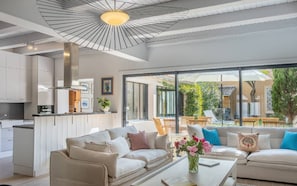 Un salon moderne avec un ensemble de canapés, une table basse agrémentée de fleurs et une vue sur la terrasse extérieure.