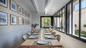 A long dining table set for a meal with framed pictures on the wall.