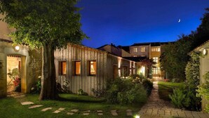 Un patio con un edificio de madera, un camino de piedra y un cielo nocturno con una luna creciente.